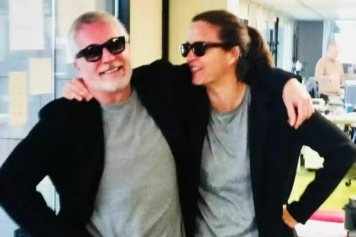David Cantero y María Casado sonrientes con gafas de sol y ropa similar se abrazan en un ambiente de oficina en Informativos Telecinco. David Cantero y María Casado sonrientes con gafas de sol y ropa similar se abrazan en un ambiente de oficina en Informativos Telecinco.
