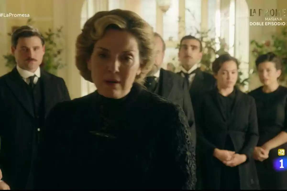 Un grupo de personas vestidas de manera formal en La Promesa como Arturo Sancho y otras se encuentra en una habitación iluminada, con Eva Martín en primer plano y varias plantas decorativas al fondo. Un grupo de personas vestidas de manera formal en La Promesa como Arturo Sancho y otras se encuentra en una habitación iluminada, con Eva Martín en primer plano y varias plantas decorativas al fondo.