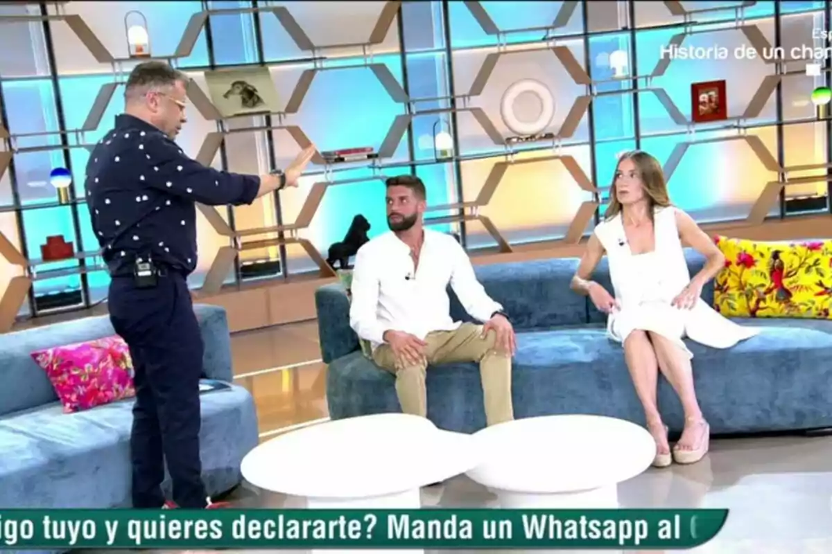 A la imatge s'observa tres persones al plató d'El Diario de Jorge, dues estan assegudes en un sofà blau mentre que la tercera persona, Jorge Javier Vázquez, està dreta davant seu, el fons del set té una decoració moderna amb prestatgeries geomètriques i diversos objectes decoratius. A la imatge s'observa tres persones al plató d'El Diario de Jorge, dues estan assegudes en un sofà blau mentre que la tercera persona, Jorge Javier Vázquez, està dreta davant seu, el fons del set té una decoració moderna amb prestatgeries geomètriques i diversos objectes decoratius.