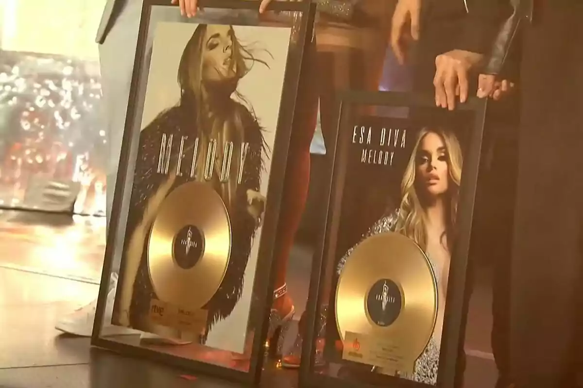 Dues persones sostenen discos d'or emmarcats amb imatges d'una artista femenina a la portada.