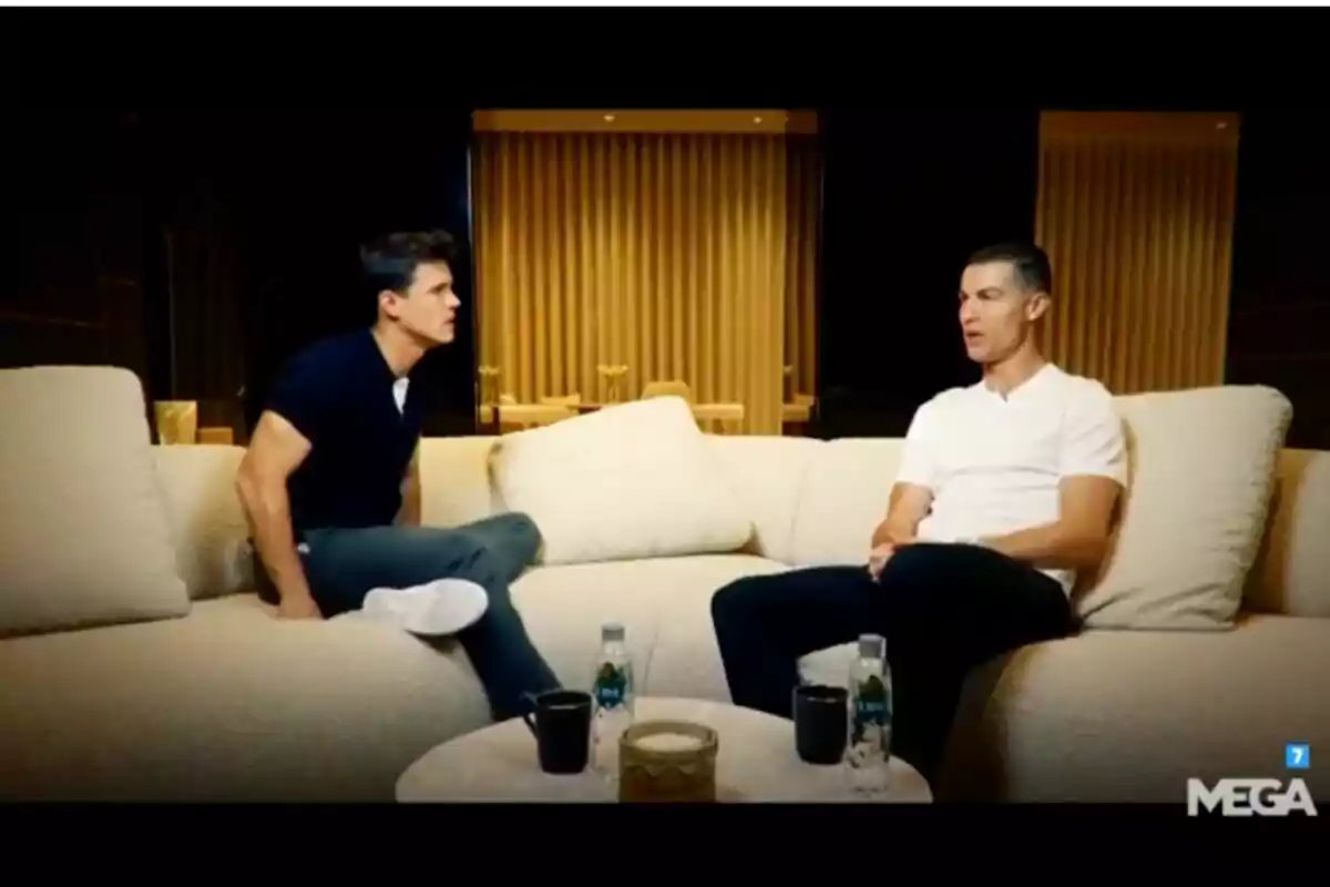 Edu Aguirre y Cristiano Ronaldo sentados en un sofá conversando en un ambiente interior con botellas de agua y tazas sobre una mesa en 'Los amigos de Edu'. Edu Aguirre y Cristiano Ronaldo sentados en un sofá conversando en un ambiente interior con botellas de agua y tazas sobre una mesa en 'Los amigos de Edu'.