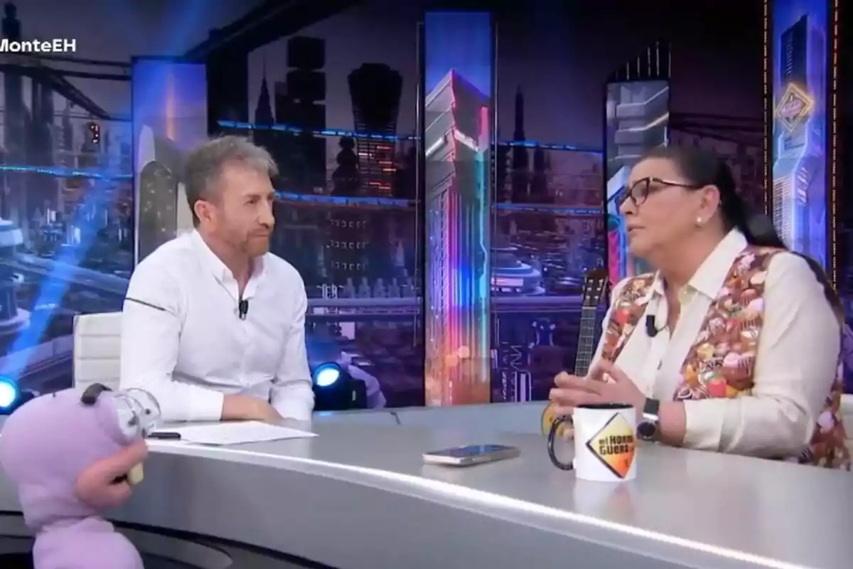 María del Monte y Pablo Motos conversan en un set de televisión con un fondo futurista y un muñeco morado en la mesa en 'El Hormiguero'. María del Monte y Pablo Motos conversan en un set de televisión con un fondo futurista y un muñeco morado en la mesa en 'El Hormiguero'.