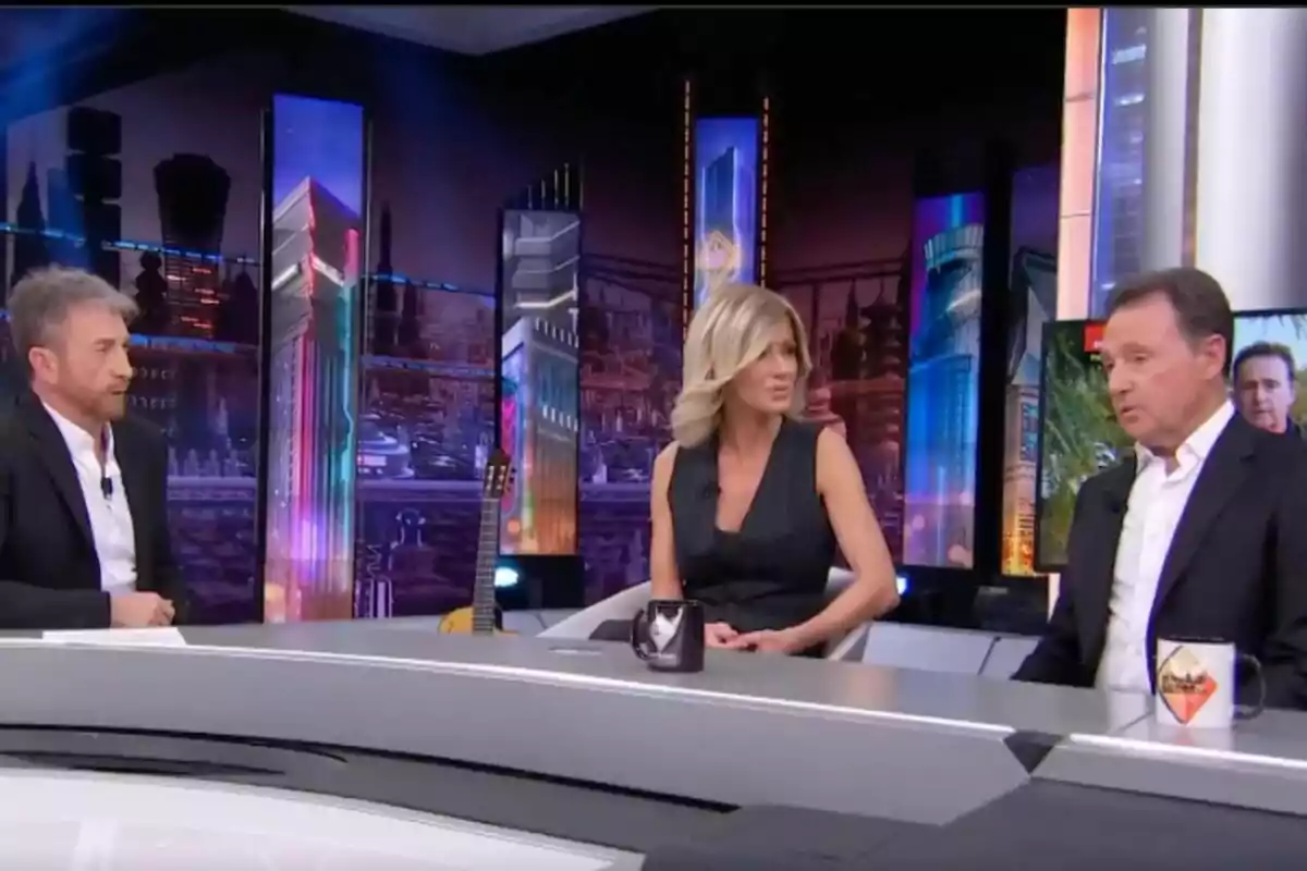 Pablo Motos, Susanna Grisoo i Matías Prats asseguts a 'El Hormiguero' amb un fons acolorit i modern, conversant al voltant d'una taula.