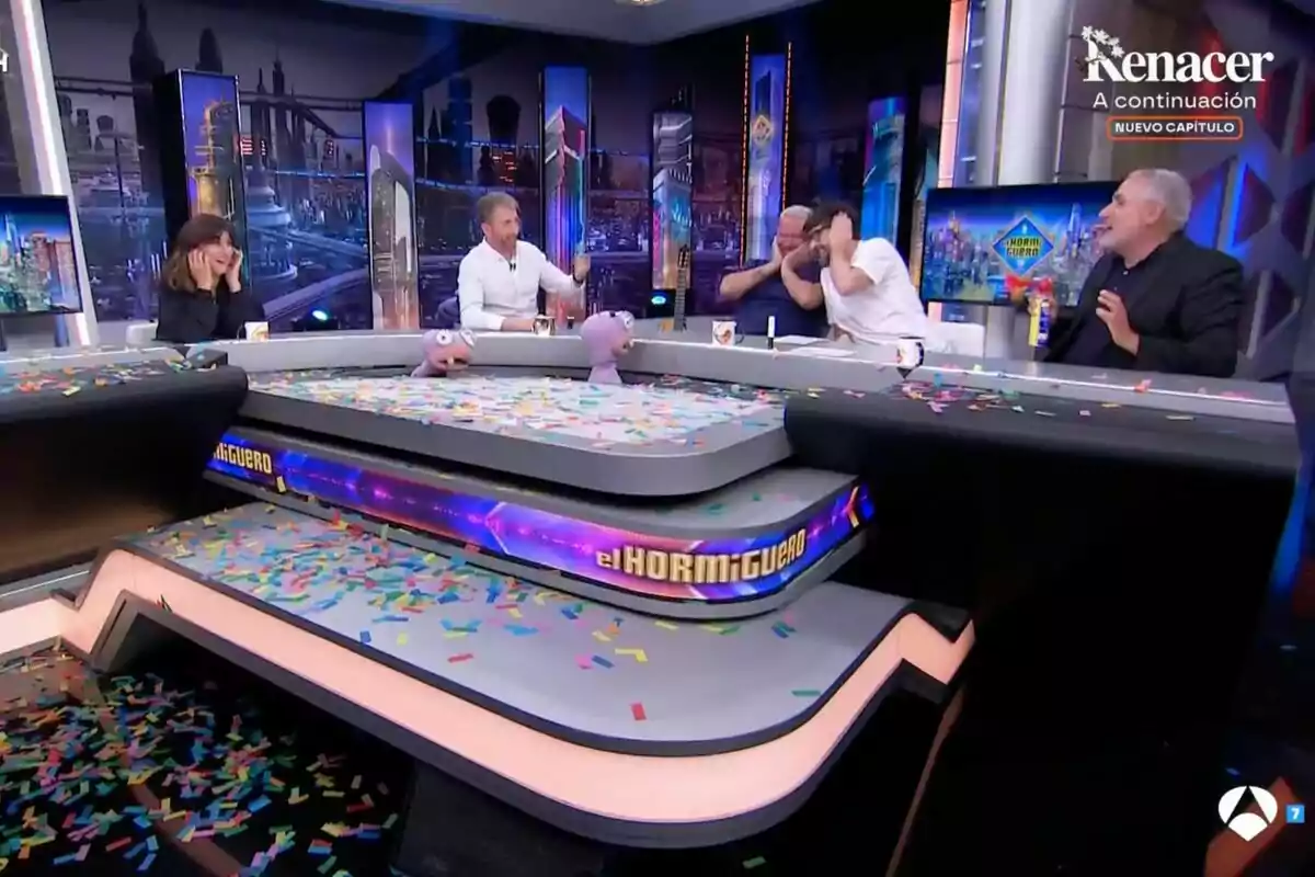 Personas sentadas alrededor de una mesa de 'El Hormiguero' cubierto de confeti, con marionetas y ambiente festivo