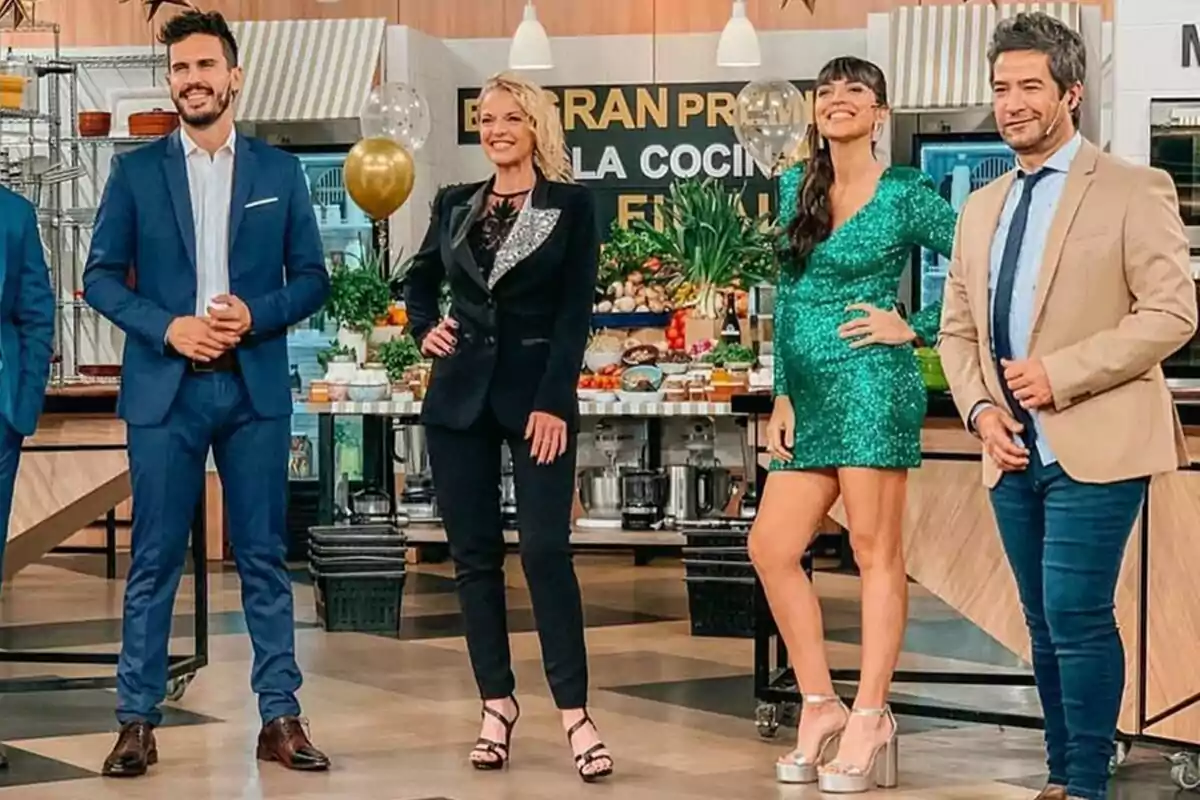 Un grupo de cuatro personas elegantemente vestidas posando en un set de cocina decorado con globos y plantas en El Gran Premio de la Cocina Un grupo de cuatro personas elegantemente vestidas posando en un set de cocina decorado con globos y plantas en El Gran Premio de la Cocina