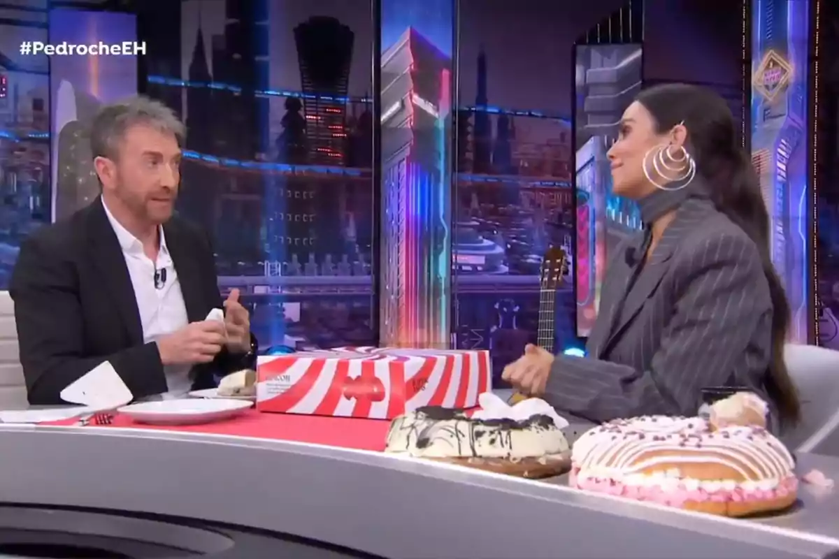 Pablo Motos i Cristina Pedroche conversen a 'El Hormiguero' amb un fons colorit i diversos pastissos sobre la taula. Pablo Motos i Cristina Pedroche conversen a 'El Hormiguero' amb un fons colorit i diversos pastissos sobre la taula.