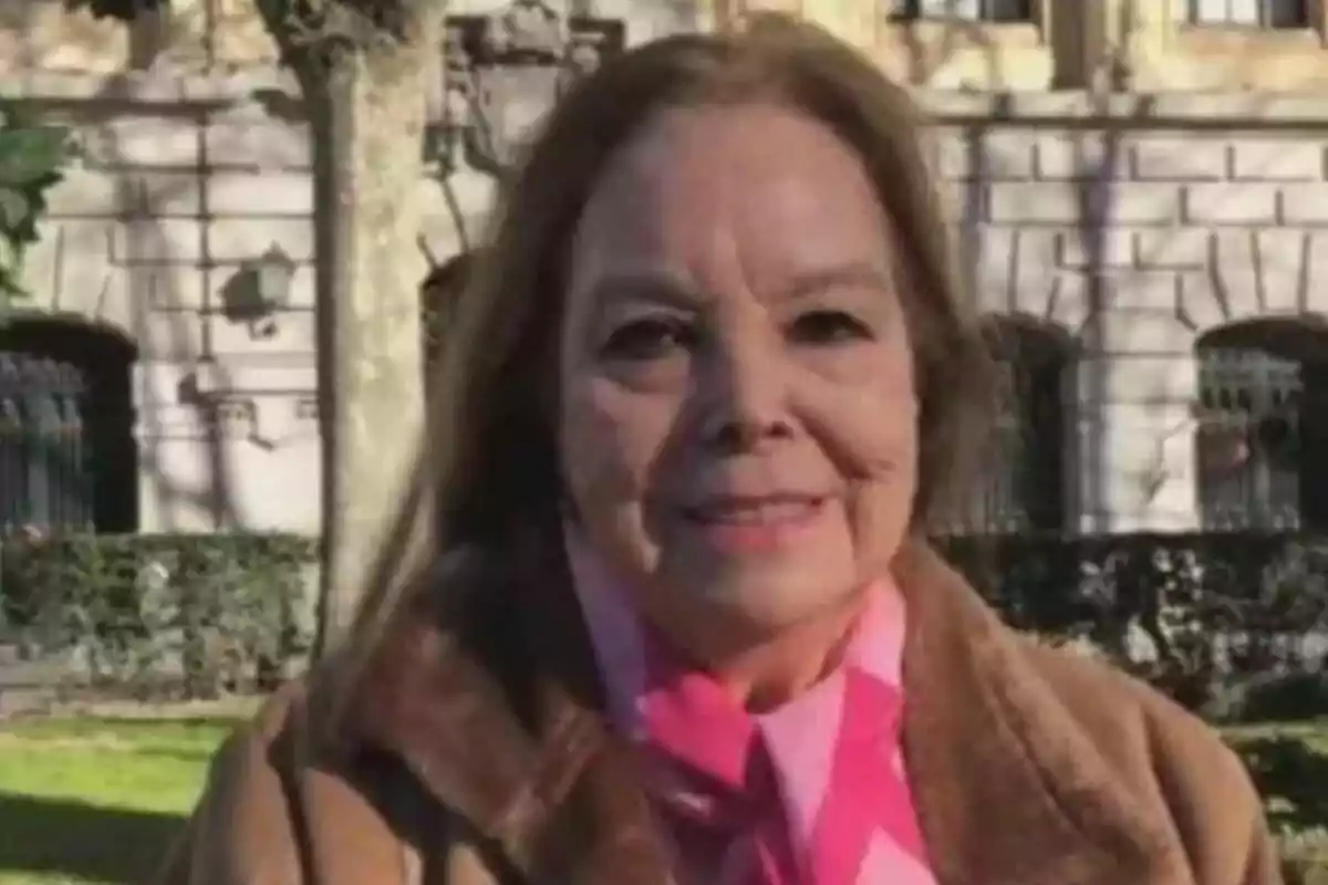 Elisa Montés de cabello castaño claro y abrigo marrón está sonriendo al aire libre con un edificio de piedra y árboles al fondo. Elisa Montés de cabello castaño claro y abrigo marrón está sonriendo al aire libre con un edificio de piedra y árboles al fondo.