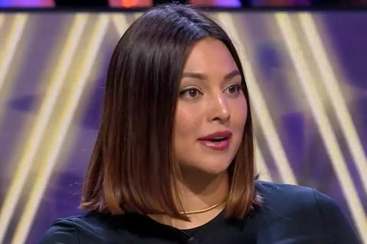Elisa Mouliaá de cabell castany i laci amb un collaret daurat està parlant a De Viernes amb un fons colorit.