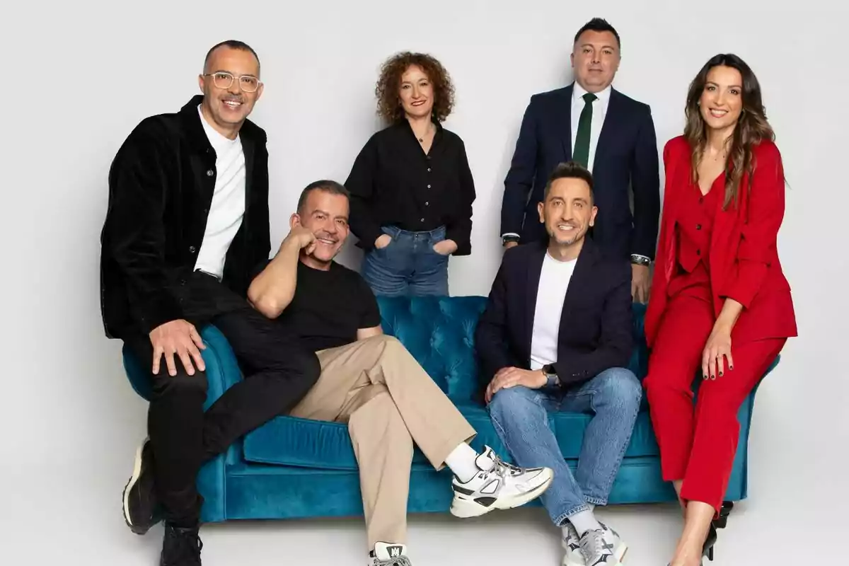 Un grupo de seis personas como Óscar Cornejo y Adrián Madrid posando juntas, algunas sentadas en un sofá azul y otras de pie, todos vestidos de manera elegante y casual. Un grupo de seis personas como Óscar Cornejo y Adrián Madrid posando juntas, algunas sentadas en un sofá azul y otras de pie, todos vestidos de manera elegante y casual.