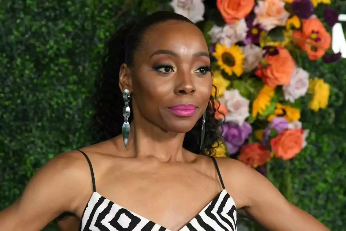 Fotografía de Erica Ash con vestido de rayas y aretes largos posando frente a un fondo de flores y vegetación. Fotografía de Erica Ash con vestido de rayas y aretes largos posando frente a un fondo de flores y vegetación.