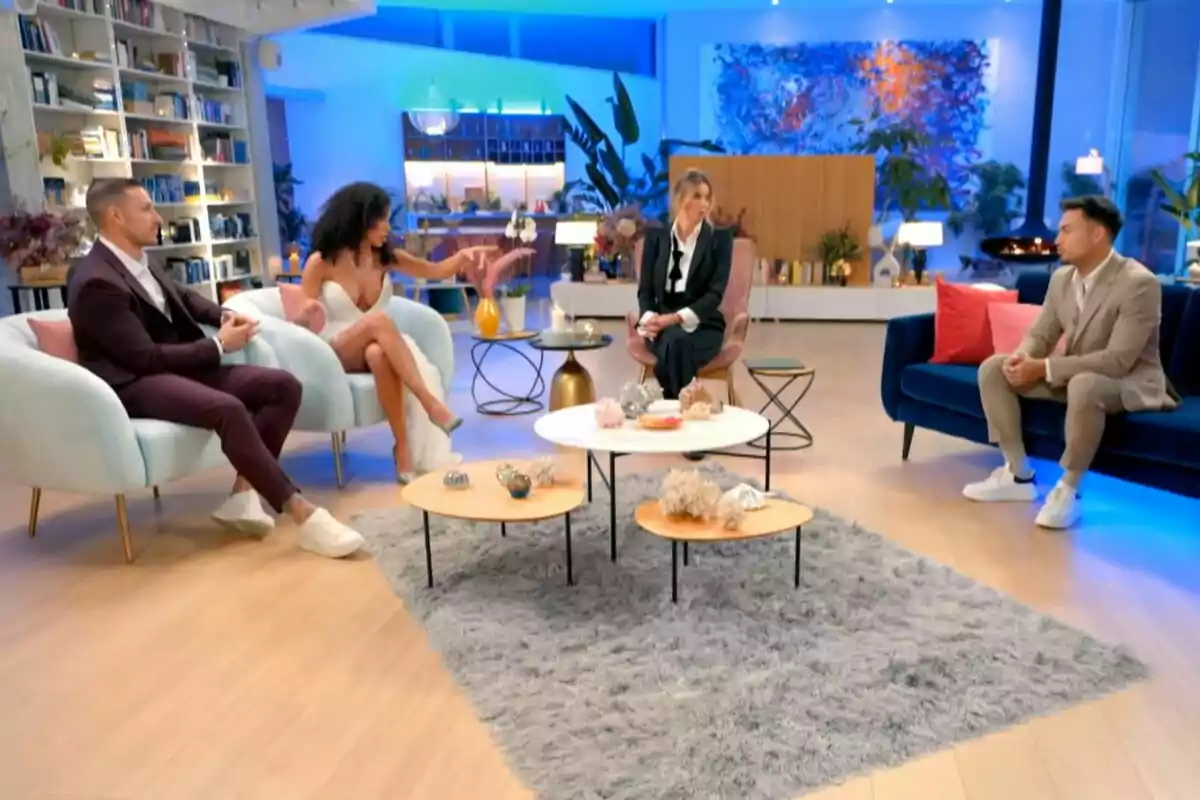 Un grupo de personas formado por Rubén Torres, Bayan, Sandra Barneda y Eros sentadas en un moderno salón con decoración elegante y luces azules en La Isla de las Tentaciones. Un grupo de personas formado por Rubén Torres, Bayan, Sandra Barneda y Eros sentadas en un moderno salón con decoración elegante y luces azules en La Isla de las Tentaciones.