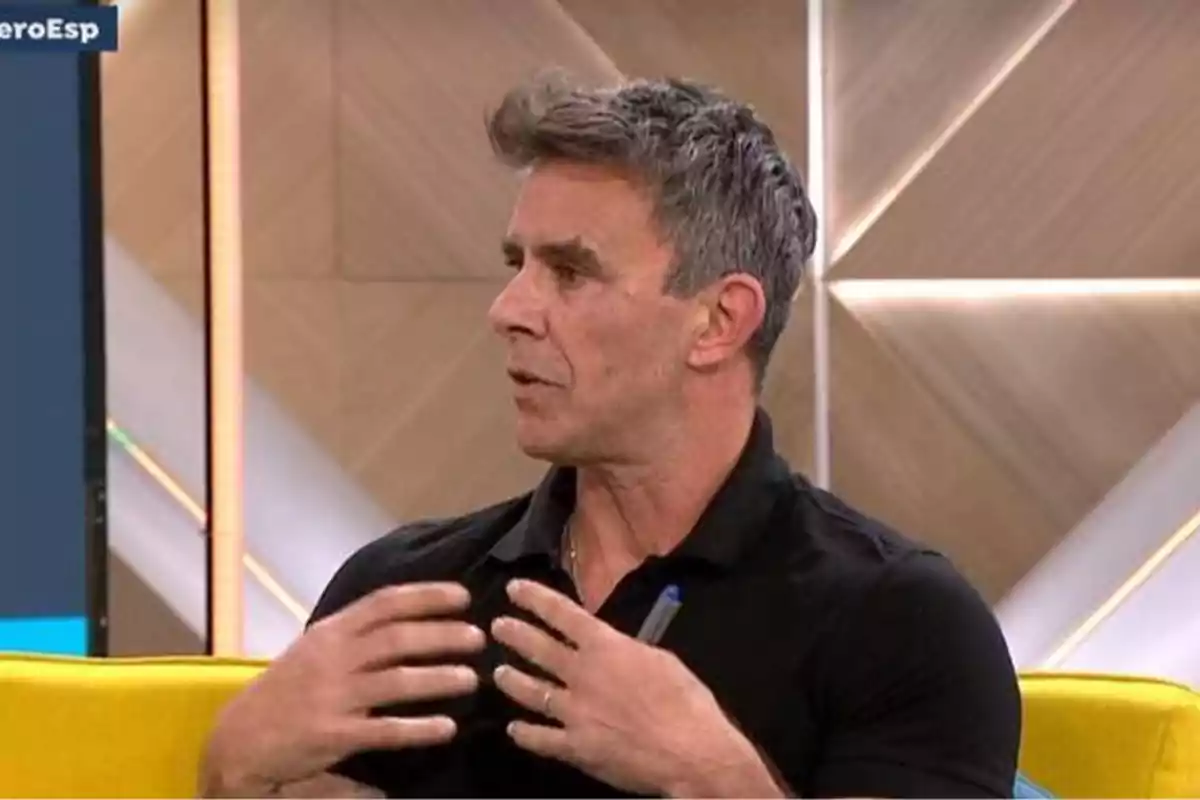Alonso Caparrós de cabello canoso y camisa negra está hablando gesticulando con las manos en un set de televisión con fondo geométrico. Captura de 'Espejo Público' Alonso Caparrós de cabello canoso y camisa negra está hablando gesticulando con las manos en un set de televisión con fondo geométrico. Captura de 'Espejo Público'