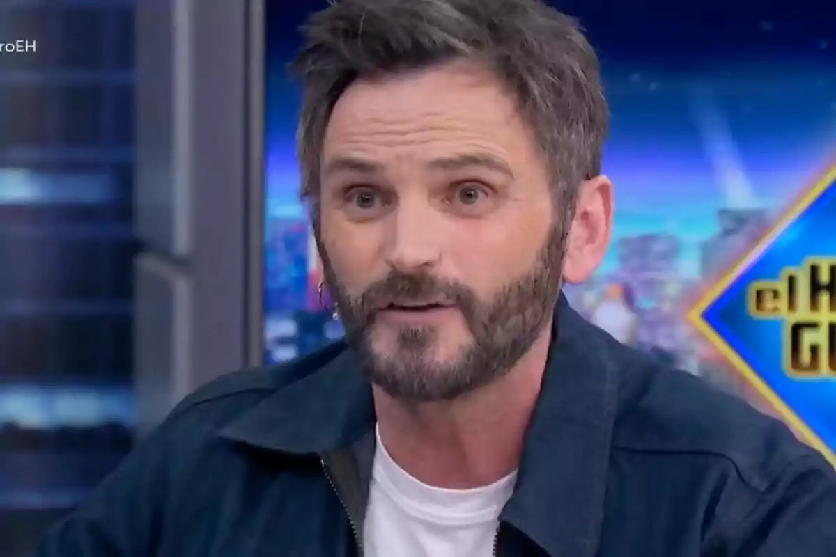 Fernando Tejero amb barba i cabell fosc a 'El Hormiguero' amb un fons acolorit.