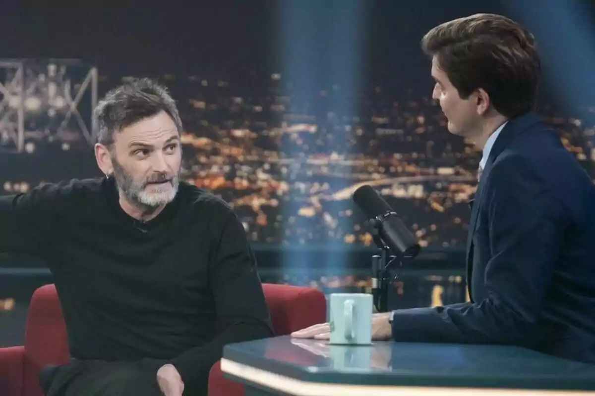 Fernando Tejero conversando con Marc Giró en Late Xou con un fondo de luces de ciudad. Fernando Tejero conversando con Marc Giró en Late Xou con un fondo de luces de ciudad.