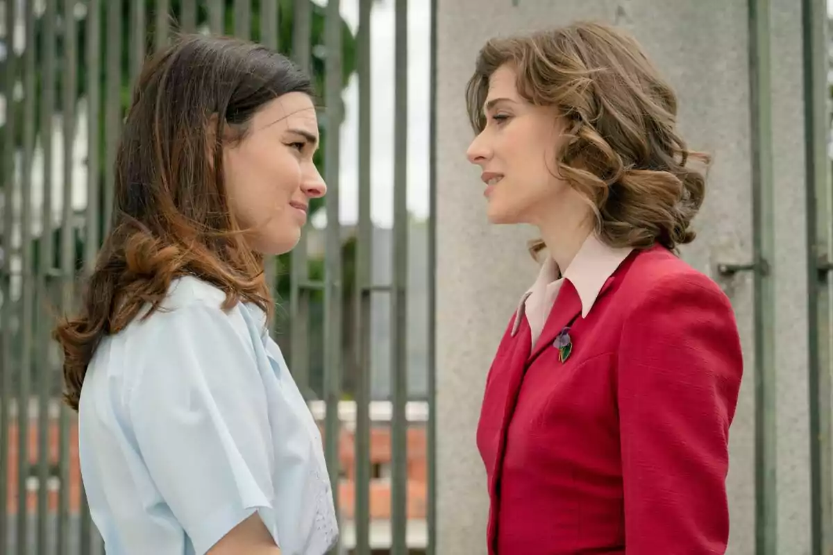 Fotografia de Marta Belmonte i Alba Brunet davant d'una reixa, una vestida amb una camisa blanca i l'altra amb un vestit vermell a Sueños de Libertad Fotografia de Marta Belmonte i Alba Brunet davant d'una reixa, una vestida amb una camisa blanca i l'altra amb un vestit vermell a Sueños de Libertad