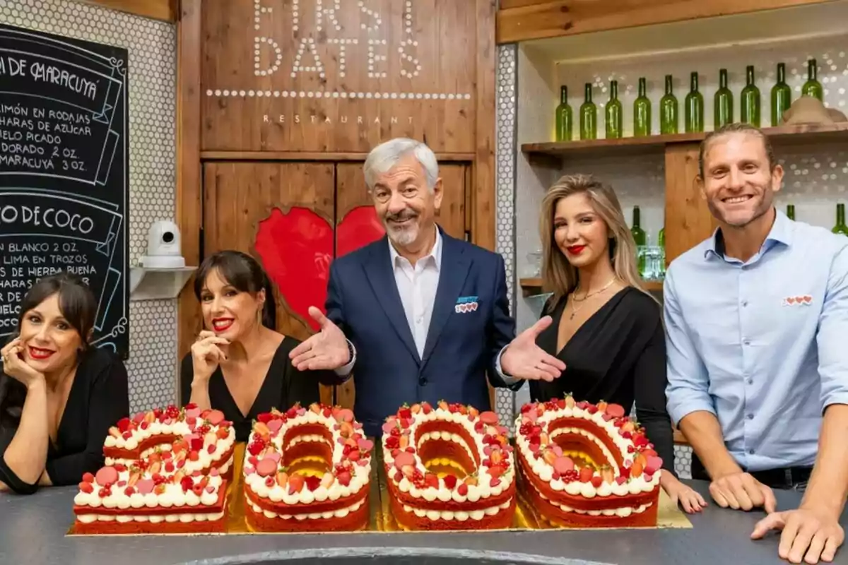 Un grup de persones com Carlos Sobera, Matías Roures o Laura Boado somriu amb un pastís amb forma de número 200 en un restaurant decorat amb ampolles verdes i un fons de fusta a First Dates. Un grup de persones com Carlos Sobera, Matías Roures o Laura Boado somriu amb un pastís amb forma de número 200 en un restaurant decorat amb ampolles verdes i un fons de fusta a First Dates.