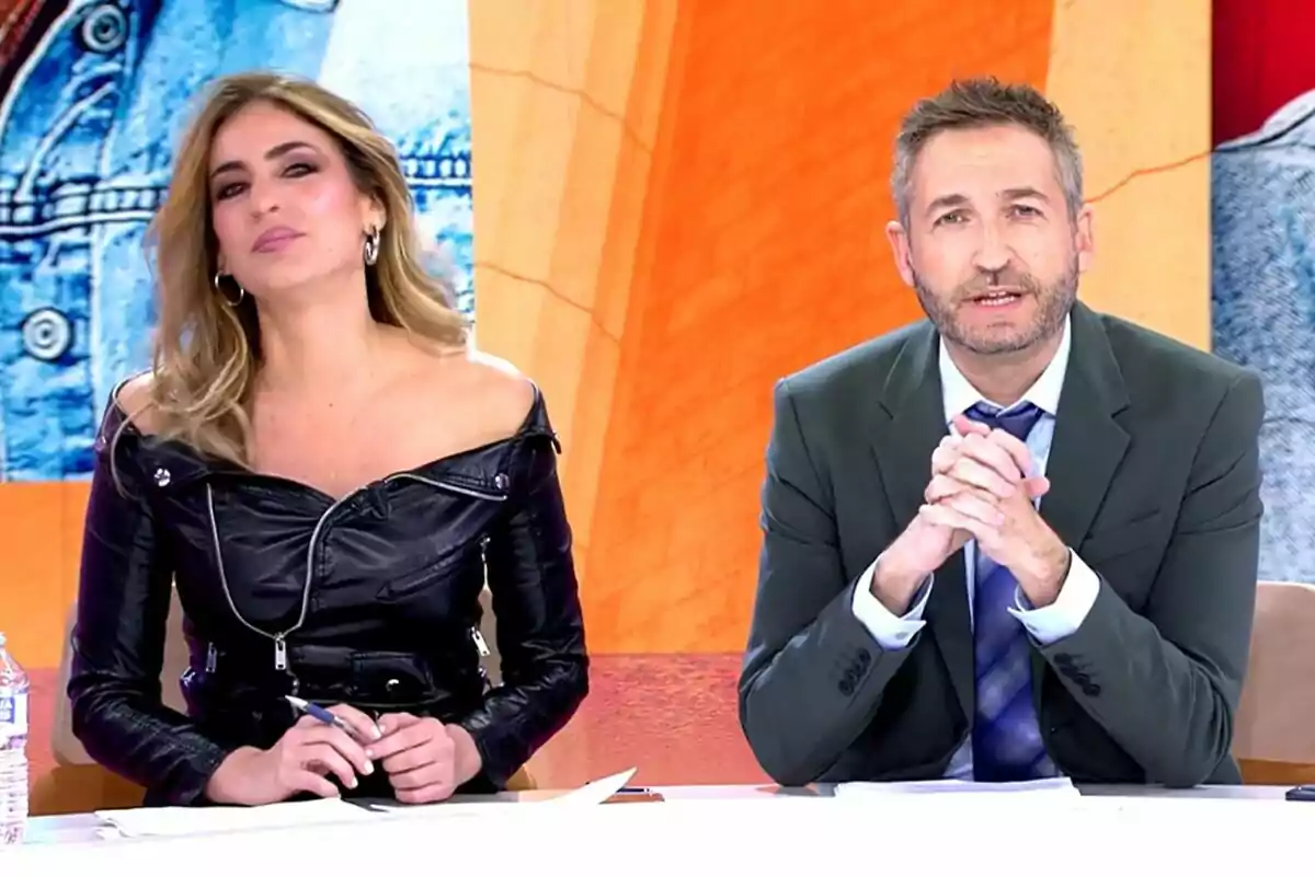 Verónica Dulanto i Frank Blanco estan asseguts en un plató acolorit de TardeAR, un d'ells porta una jaqueta de cuir negra i l'altre un vestit formal.