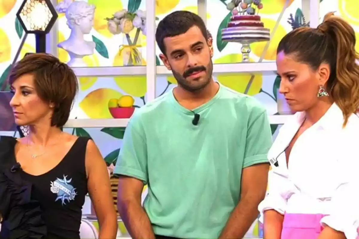 Adela González, Germán González i Nuria Marín estan drets en un set de televisió decorat amb motius de fruites i pastissos, una dona amb cabell curt i fosc porta una samarreta negra, un home amb barba i bigoti vesteix una samarreta verda, i una altra dona amb els cabells recollits porta una brusa blanca i una faldilla rosa al plató de Sálvame. Adela González, Germán González i Nuria Marín estan drets en un set de televisió decorat amb motius de fruites i pastissos, una dona amb cabell curt i fosc porta una samarreta negra, un home amb barba i bigoti vesteix una samarreta verda, i una altra dona amb els cabells recollits porta una brusa blanca i una faldilla rosa al plató de Sálvame.