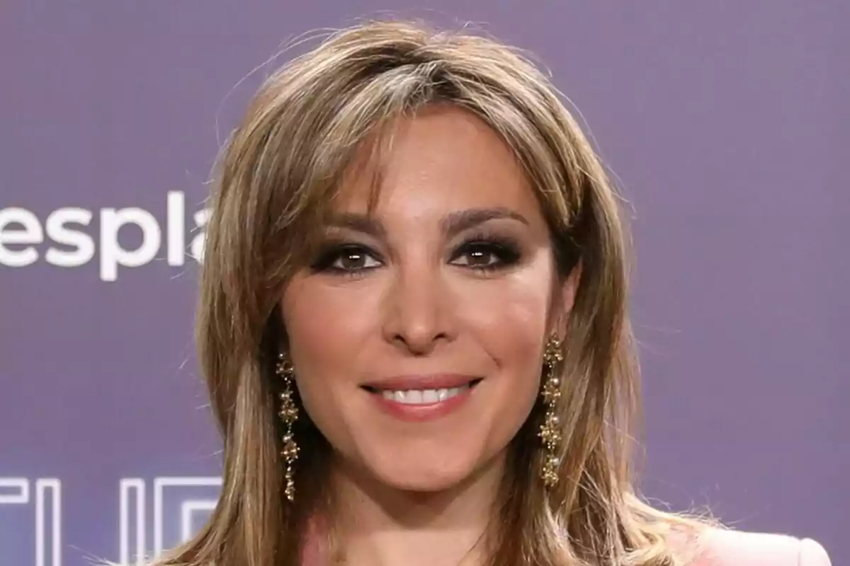 Primer pla de Gisela Lladó somrient amb uns arracades grans i un fons acolorit durant la presentació de Tu Cara Me Suena.