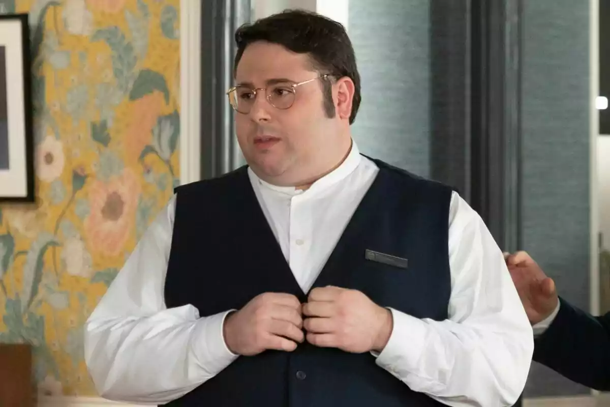 Gonzalo Caps con gafas y chaleco oscuro está de pie en una habitación con papel tapiz floral en 4 Estrellas. Gonzalo Caps con gafas y chaleco oscuro está de pie en una habitación con papel tapiz floral en 4 Estrellas.