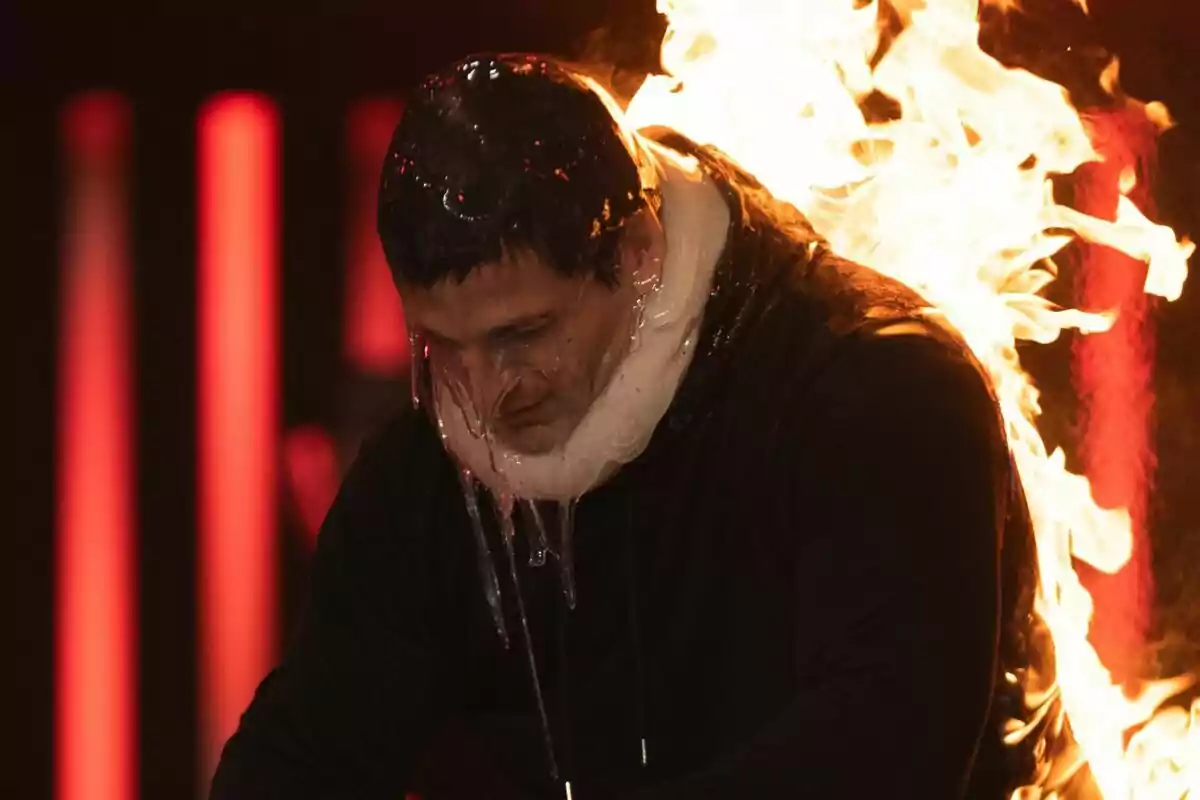 Gotzon Mantuliz con protección de gel en la cabeza y el cuello está rodeado de llamas en un entorno oscuro en El Desafío.