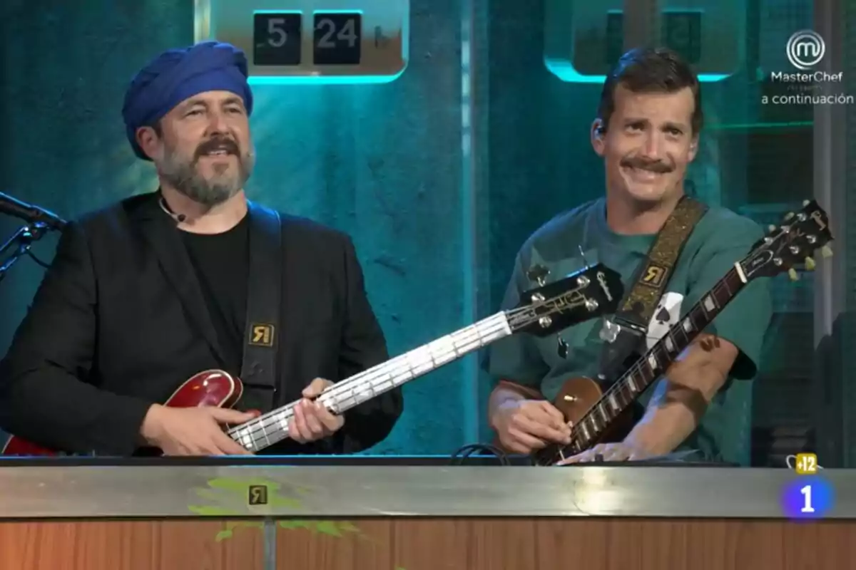Ricardo Castella y Grison en el plató de La Revuelta, uno con un turbante azul y una guitarra eléctrica, el otro con una camiseta verde y una guitarra eléctrica, ambos sonriendo. Ricardo Castella y Grison en el plató de La Revuelta, uno con un turbante azul y una guitarra eléctrica, el otro con una camiseta verde y una guitarra eléctrica, ambos sonriendo.