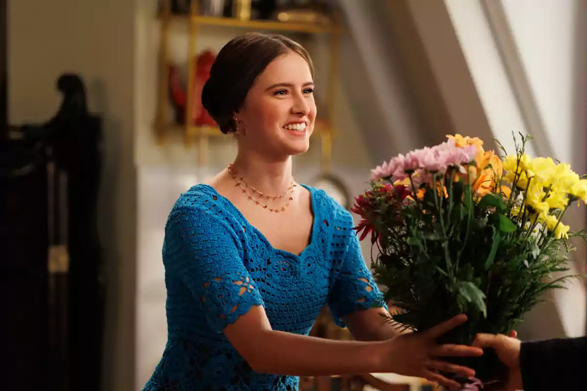 Helena Cortesina sonriente con un vestido azul recibe un ramo de flores de colores en La Moderna. Helena Cortesina sonriente con un vestido azul recibe un ramo de flores de colores en La Moderna.