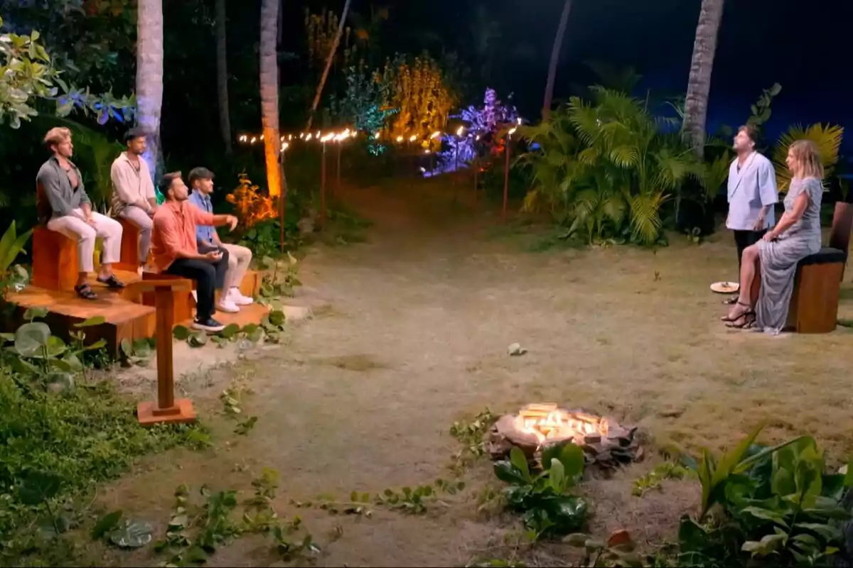 Los tentadores Montoya, Álvaro, Tadeo y Eros están sentados ante Sandra Barneda y Manuel Rodríguez en un entorno al aire libre iluminado por luces y rodeado de vegetación, con una fogata en el centro en La Isla de las Tentaciones. Los tentadores Montoya, Álvaro, Tadeo y Eros están sentados ante Sandra Barneda y Manuel Rodríguez en un entorno al aire libre iluminado por luces y rodeado de vegetación, con una fogata en el centro en La Isla de las Tentaciones.