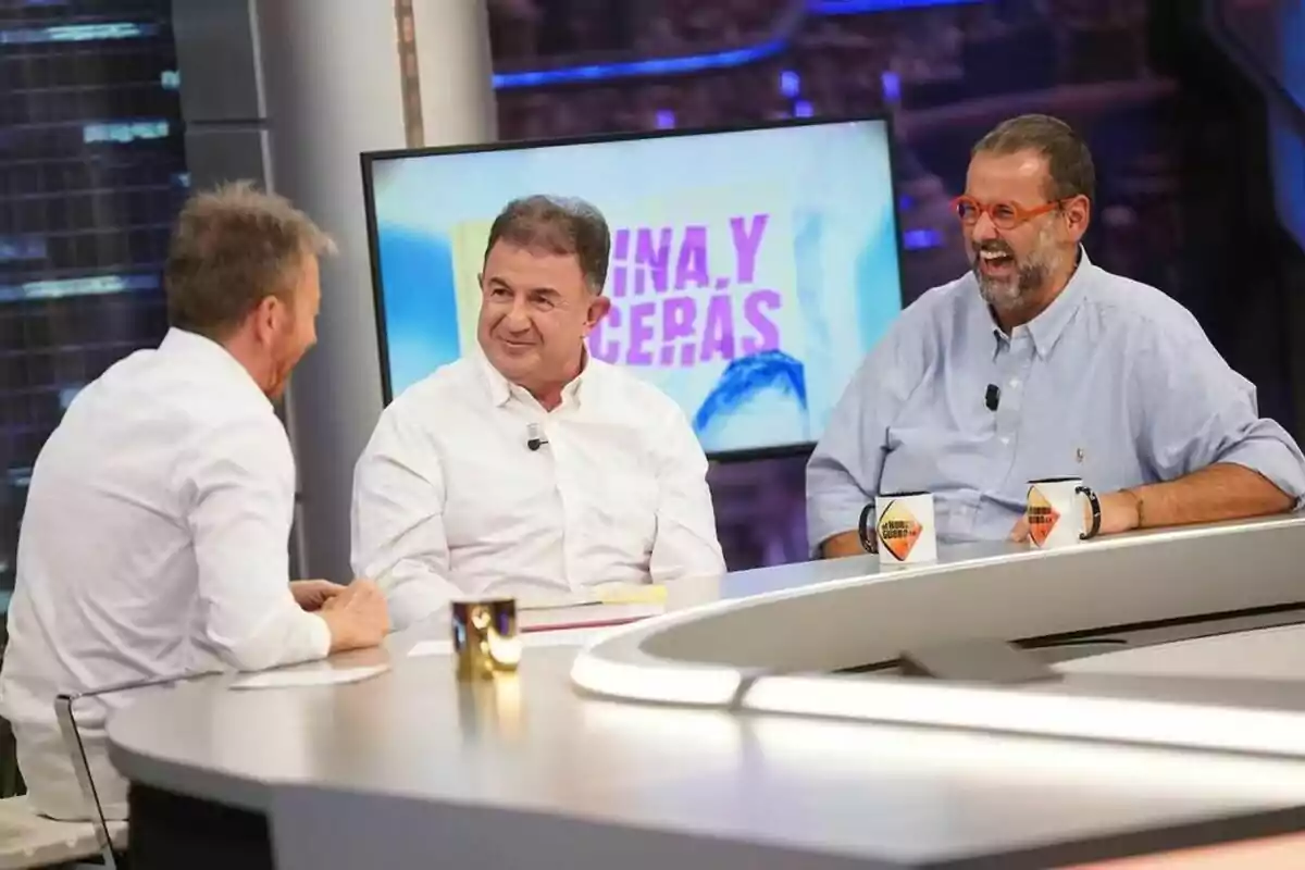 Martín Berasategui y David de Jorge junto a Pablo Motos conversan y ríen en El Hormiguero con una pantalla de fondo que muestra texto en colores brillantes. Martín Berasategui y David de Jorge junto a Pablo Motos conversan y ríen en El Hormiguero con una pantalla de fondo que muestra texto en colores brillantes.