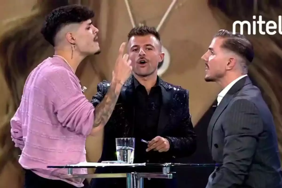 Álvaro, Tadeo e Iban García están en Los vecinos de la casa de al lado, dos de ellas parecen estar discutiendo mientras una tercera persona, que está en el centro, observa y sostiene un micrófono.