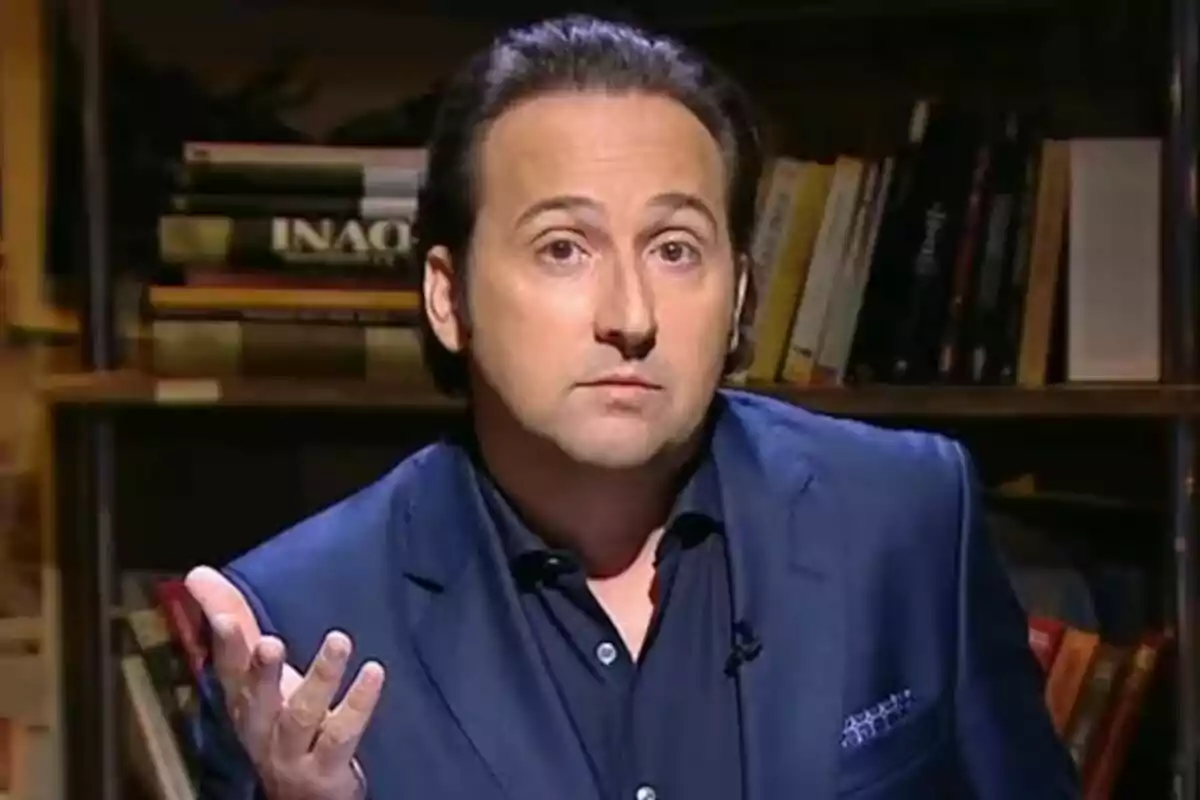 Iker Jiménez con expresión pensativa y gesto de pregunta, vestido con un traje azul, frente a una estantería con libros en su programa 'Cuarto Milenio' Iker Jiménez con expresión pensativa y gesto de pregunta, vestido con un traje azul, frente a una estantería con libros en su programa 'Cuarto Milenio'