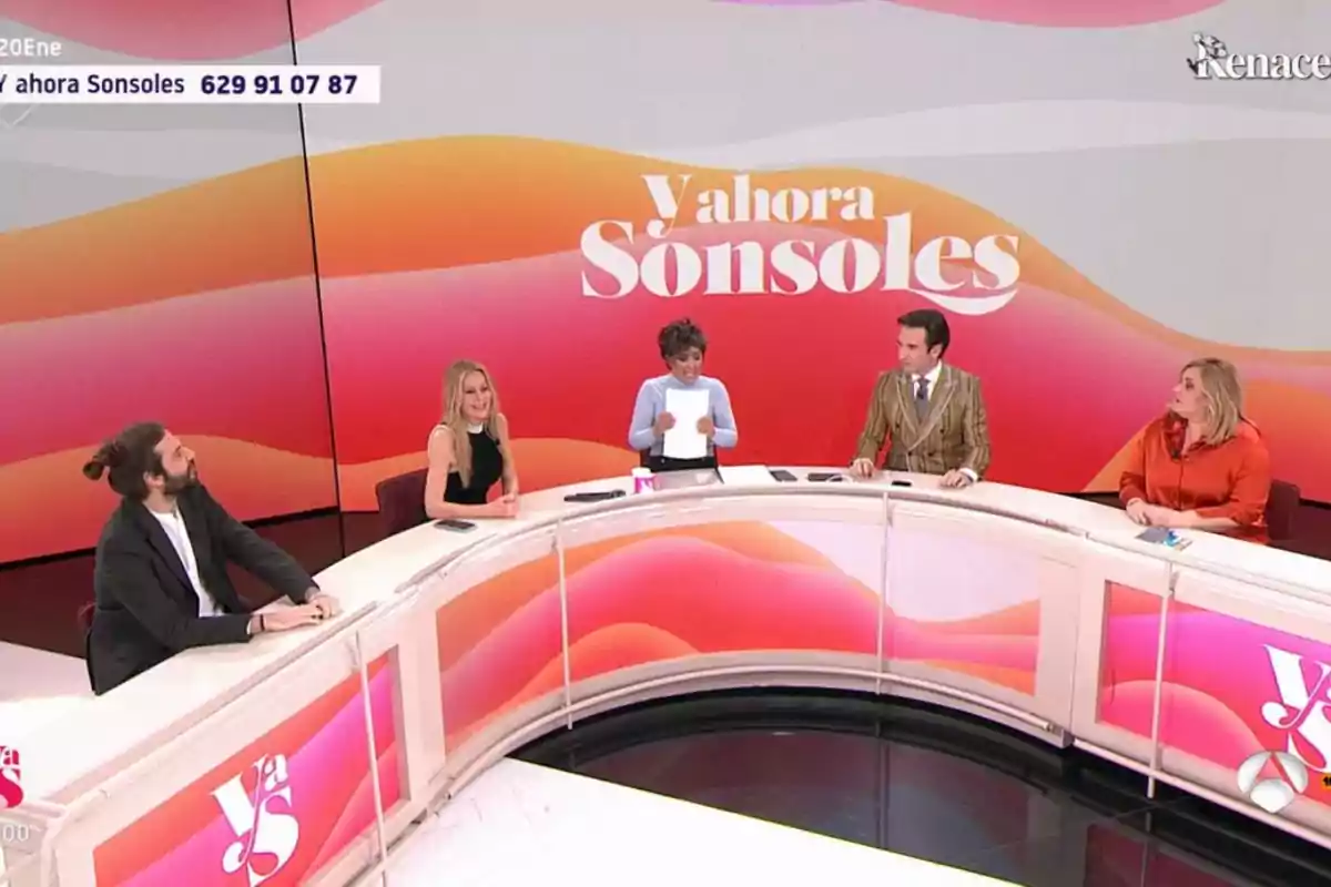Un grupo de personas está sentado en un set de televisión con un fondo colorido que dice Un grupo de personas está sentado en un set de televisión con un fondo colorido que dice