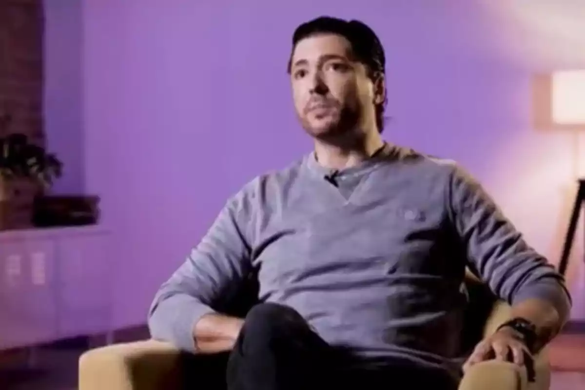 Ángel Cristo sentado en una silla con un fondo morado. Ángel Cristo sentado en una silla con un fondo morado.
