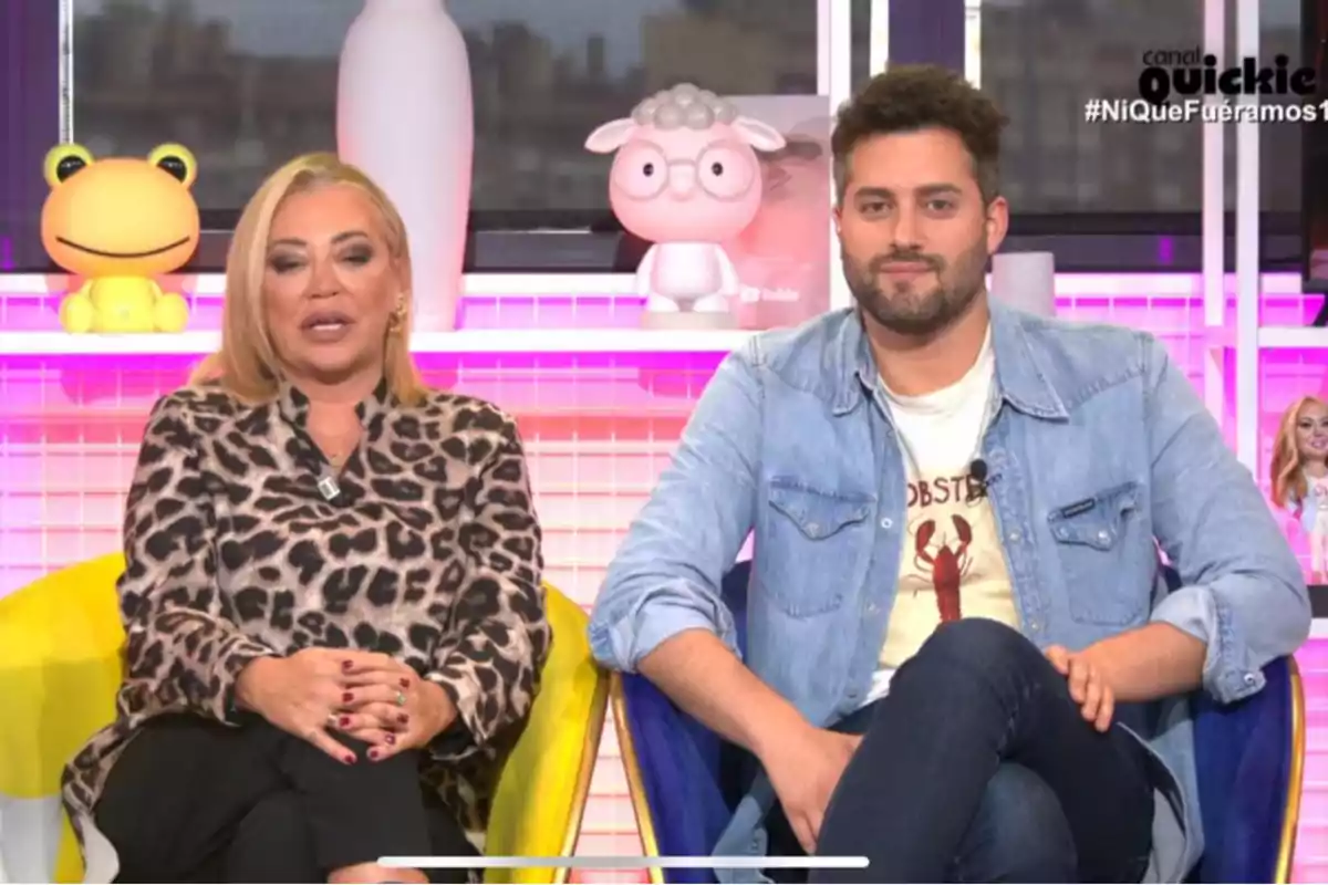 Belén Esteban y Javi de Hoyos sentados en un set de televisión con juguetes y decoración colorida al fondo. Belén Esteban y Javi de Hoyos sentados en un set de televisión con juguetes y decoración colorida al fondo.
