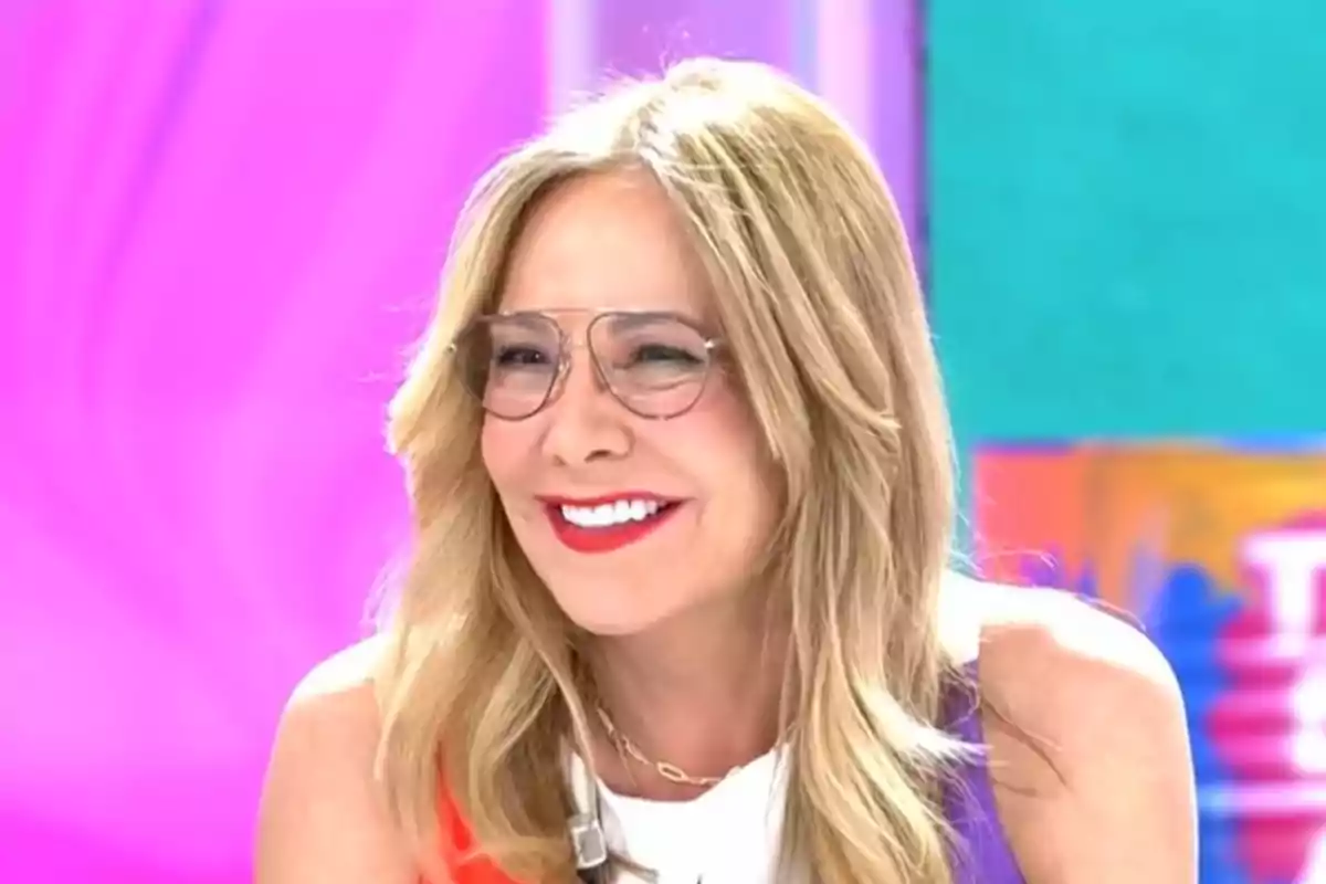 Una persona somrient amb ulleres i cabell ros en un fons acolorit. Una persona somrient amb ulleres i cabell ros en un fons acolorit.