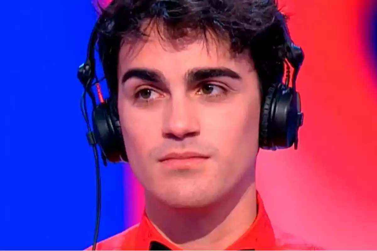 Borjamina con auriculares y camisa roja en un fondo azul y rojo.