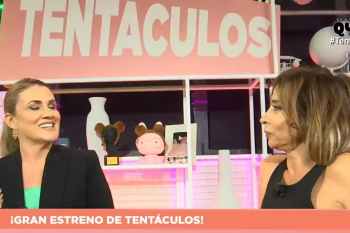 María Patiño y Carlota Corredera conversan en un set de televisión con un cartel que dice María Patiño y Carlota Corredera conversan en un set de televisión con un cartel que dice