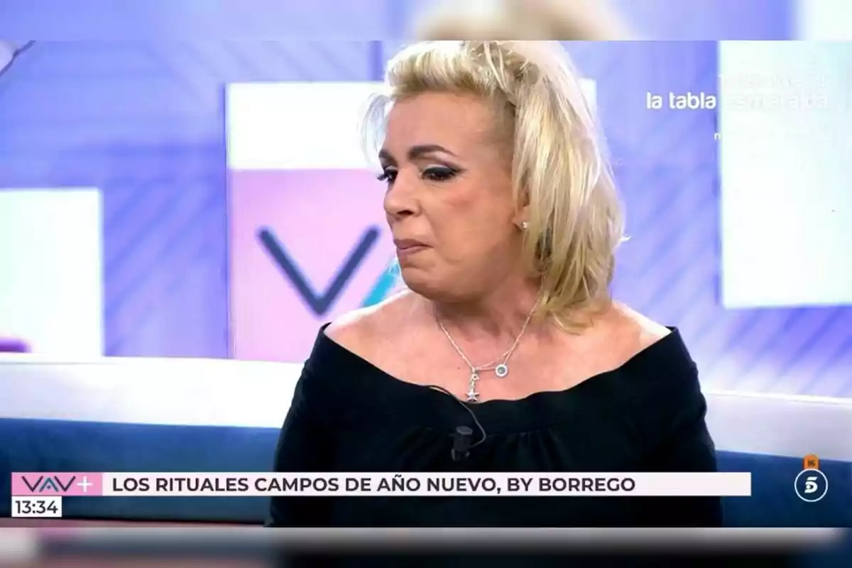 Pla curt de Carmen Borrego amb un vestit negre apareix en un programa de televisió amb gràfics en pantalla que esmenten rituals de Cap d'Any. Pla curt de Carmen Borrego amb un vestit negre apareix en un programa de televisió amb gràfics en pantalla que esmenten rituals de Cap d'Any.