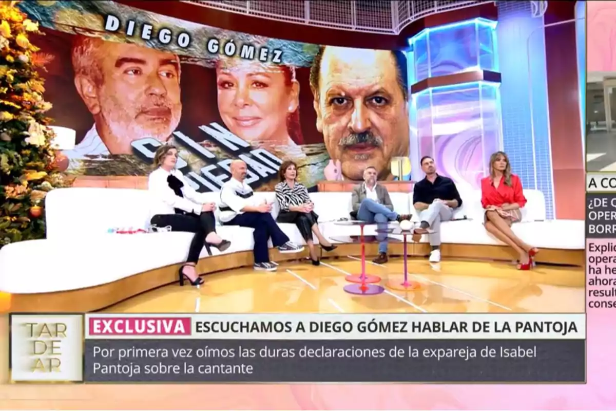 Un grupo de personas sentadas en un plató de televisión con una pantalla grande detrás que muestra imágenes de dos personas y el texto Un grupo de personas sentadas en un plató de televisión con una pantalla grande detrás que muestra imágenes de dos personas y el texto