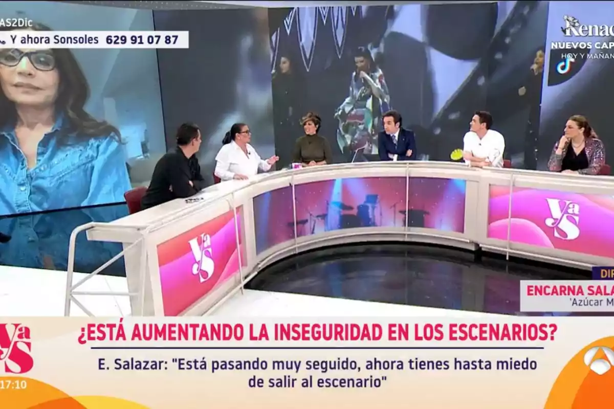 Un grupo de personas participa en un programa de televisión en un estudio con una gran pantalla detrás de ellos mostrando a una mujer y un video de fondo. Un grupo de personas participa en un programa de televisión en un estudio con una gran pantalla detrás de ellos mostrando a una mujer y un video de fondo.