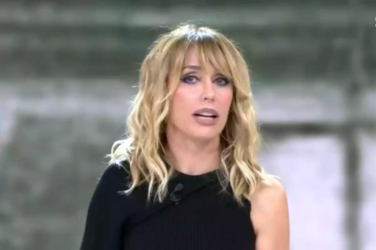 Emma García con cabello rubio y ondulado lleva un vestido negro de un solo hombro mientras mira hacia adelante.