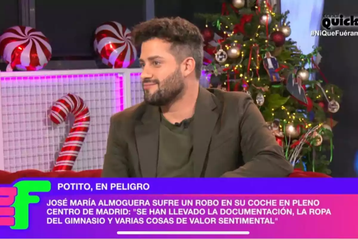 Javi de Hoyos con barba y cabello rizado está sentado en un set decorado con motivos navideños, incluyendo bastones de caramelo y un árbol de Navidad iluminado. Javi de Hoyos con barba y cabello rizado está sentado en un set decorado con motivos navideños, incluyendo bastones de caramelo y un árbol de Navidad iluminado.