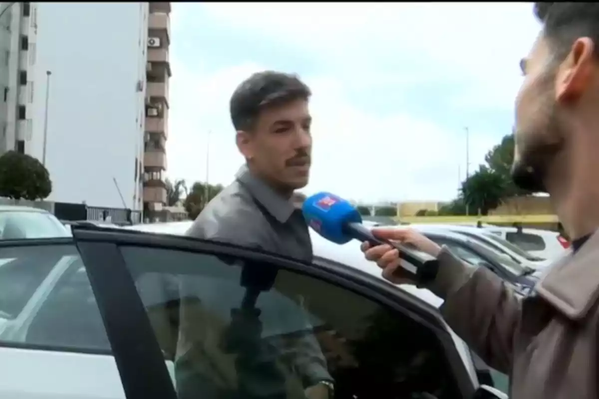 Luitingo està sent entrevistat mentre es troba al costat d'un cotxe en un aparcament. Luitingo està sent entrevistat mentre es troba al costat d'un cotxe en un aparcament.