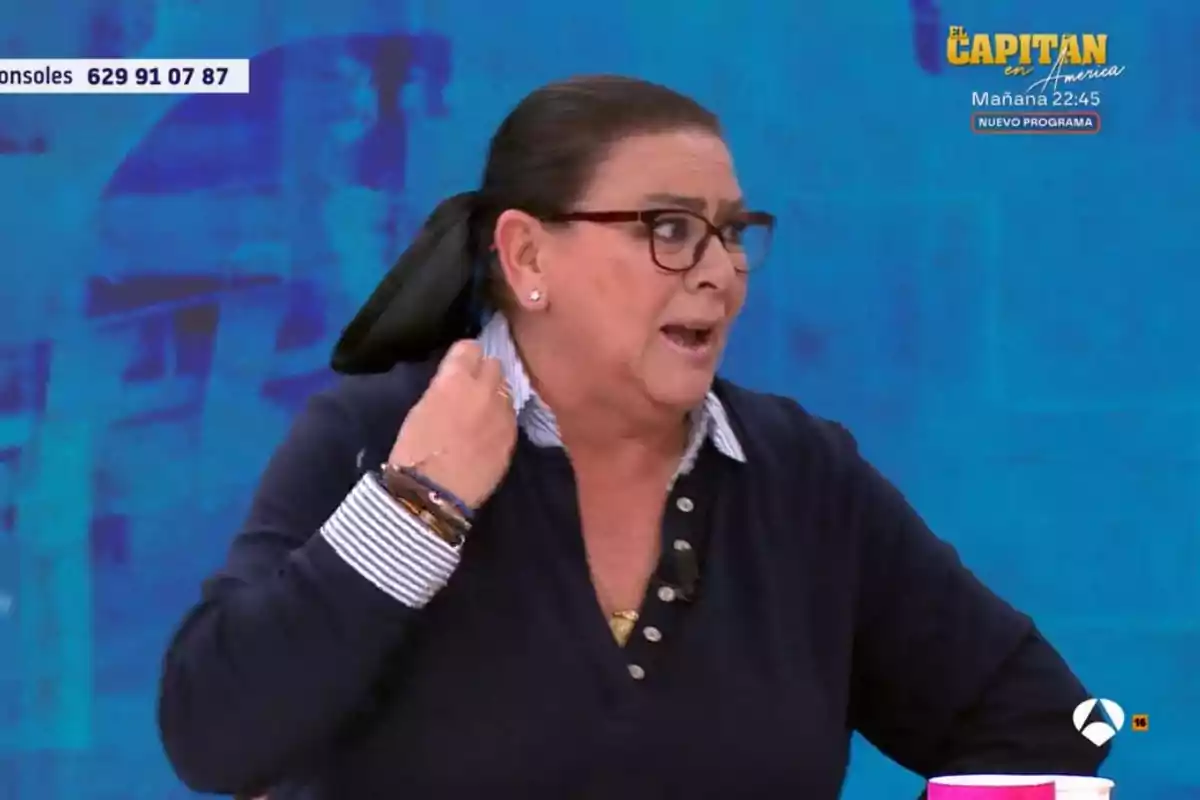 Una persona amb ulleres i cabells recollits està parlant en un programa de televisió, amb un fons blau i gràfics en pantalla. Una persona amb ulleres i cabells recollits està parlant en un programa de televisió, amb un fons blau i gràfics en pantalla.