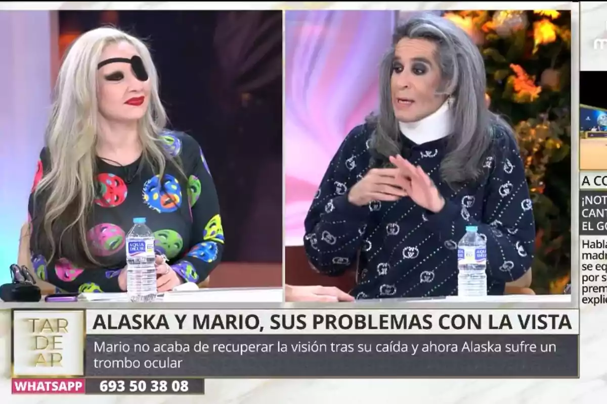 Alaska y Mario Vaquerizo sentados en un programa de televisión, Alaska lleva un parche en el ojo y un vestido con estampado colorido, mientras Mario tiene el cabello largo y canoso y viste un suéter oscuro con patrones claros, ambas tienen botellas de agua sobre la mesa. Alaska y Mario Vaquerizo sentados en un programa de televisión, Alaska lleva un parche en el ojo y un vestido con estampado colorido, mientras Mario tiene el cabello largo y canoso y viste un suéter oscuro con patrones claros, ambas tienen botellas de agua sobre la mesa.