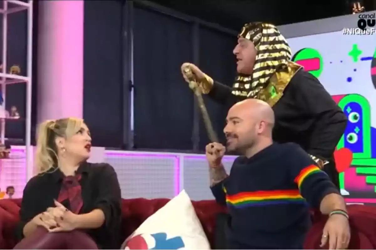 Marta Riesco y Víctor Sandoval en un set de televisión, una de ellas vestida con un disfraz de faraón, interactúan animadamente mientras están sentadas en un sofá rojo. Marta Riesco y Víctor Sandoval en un set de televisión, una de ellas vestida con un disfraz de faraón, interactúan animadamente mientras están sentadas en un sofá rojo.