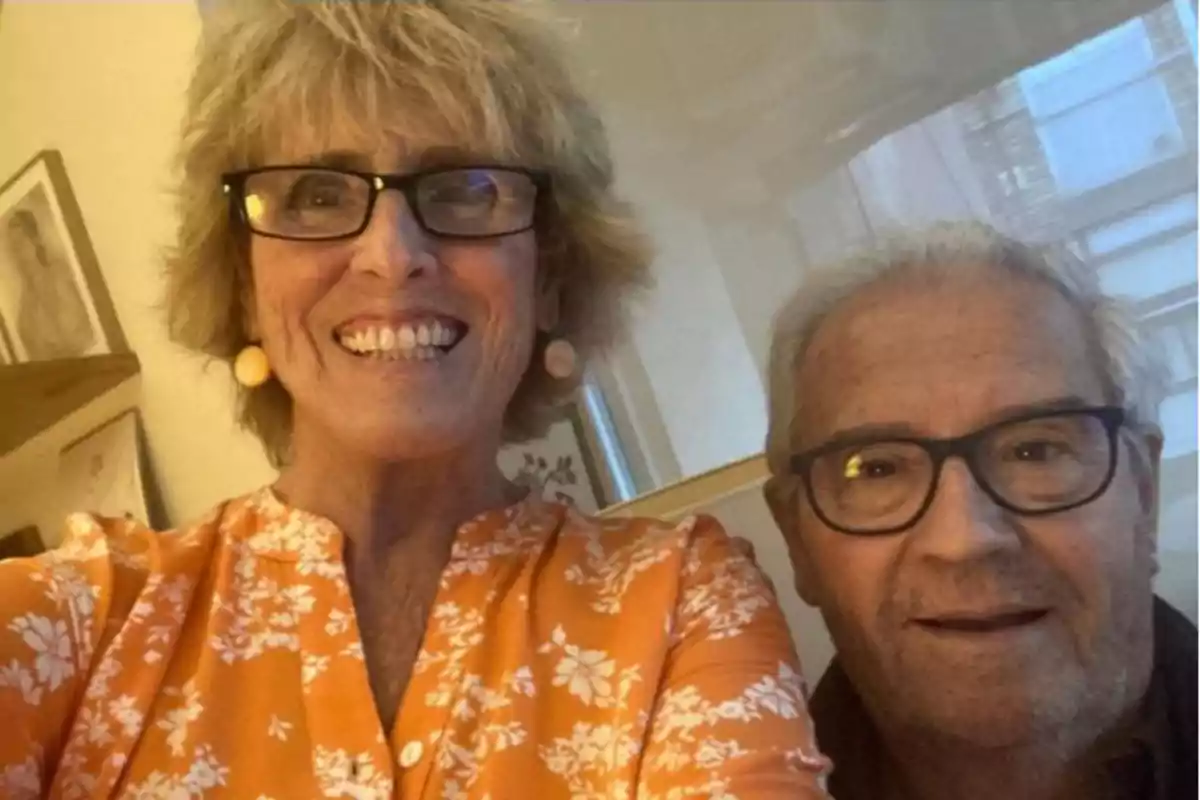 Mercedes Milá y su cuñado Paco sonrientes posando para una selfie en un interior iluminado. Mercedes Milá y su cuñado Paco sonrientes posando para una selfie en un interior iluminado.