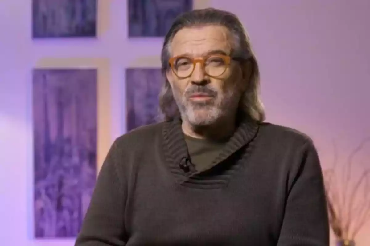 Pepe Navarro con gafas y barba está sentado frente a un fondo con cuadros. Pepe Navarro con gafas y barba está sentado frente a un fondo con cuadros.