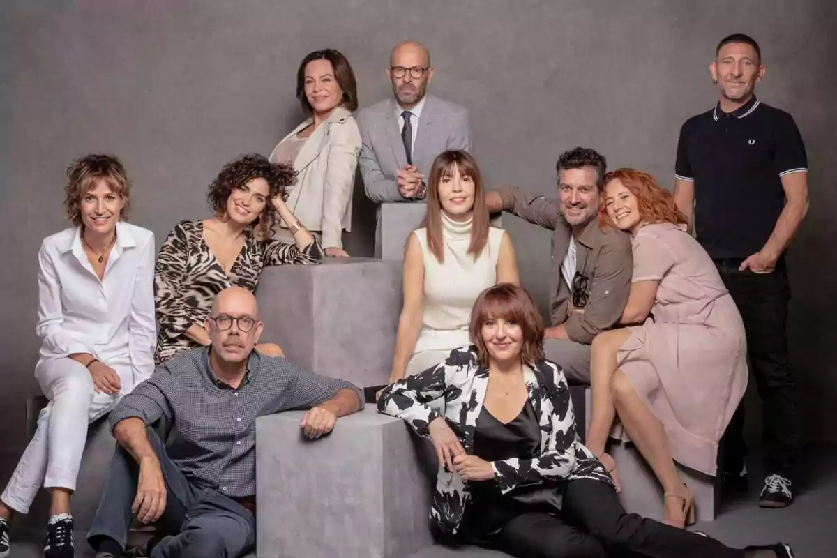 Un grup de persones posant juntes a un estudi fotogràfic amb un fons gris.