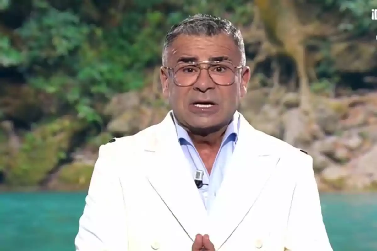 Un home amb ulleres i jaqueta blanca està parlant davant d'un fons natural. Un home amb ulleres i jaqueta blanca està parlant davant d'un fons natural.